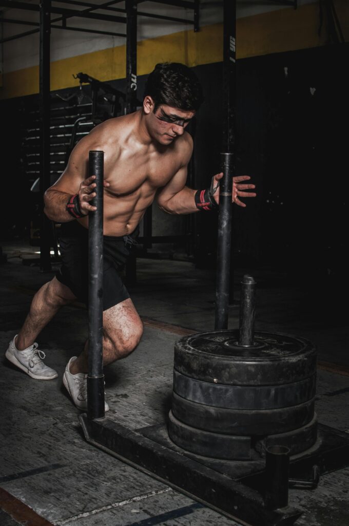 pexels photo 1552102 1552102 A muscular man pushes a weighted sled in an indoor gym, showcasing strength and endurance.